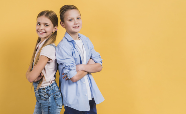 smiling-portrait-girl-boy-with-arm-crossed-standing-back-back-against-yellow-background_23-2148088983